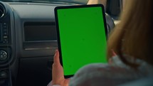 woman sitting at the passenger seat holding gadget with isolated green screen summer road trip