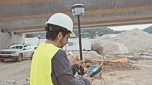 Construction engineer working with GPS equipment on a large highway construction site