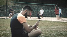 man sitting in park with his cellphone 