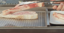 Close up slow motion shot of meat on a grilling plate in an outdoor luxury kitchen