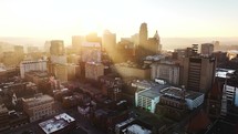 Sunrise aerial footage of downtown Cincinnati, Ohio in the fall with a light reveal and flare from the sun with plenty of buildings.