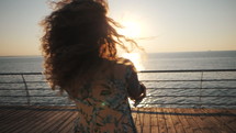 Beautiful girls spinning around wirh hands, dancing and playing on the embankment near sea or ocean. Friendship concept. Sunrise or sunset light. Adult women