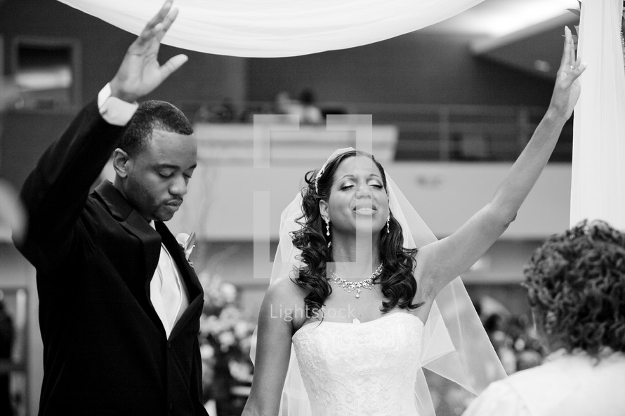 bride and groom with hands raised in praise and worship to the Lord