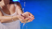 Clean stream of water pours into womans palm. Hands with gypsy boho rings holding clear aqua. Freshness, waterfall, purity, life-giving force, tropical background. High quality 4k footage