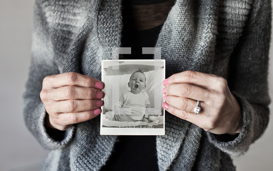 woman holding up an old baby picture