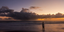man standing in the tide at sunset 