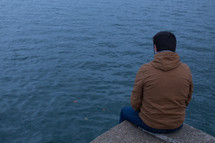 a man sitting on a rock near a lake 