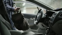 a man throwing his bag in a car and driving 