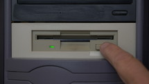 A man inserting and ejecting a vintage floppy disk on an old computer