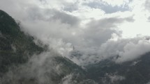 Aerial drone flying through the clouds in mountains in upward motion