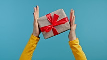 Hands of woman with gift box and bow. She is happy and flattered by attention. Present on blue background. High quality 4k footage