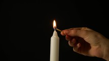 Woman Lights A Candle On A Black Background, And Then Blows It.