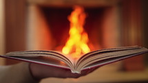 Stunning view of open book against burning fire from fireplace background. Paper literature, education concept. Hig