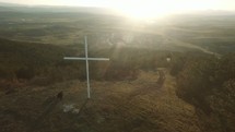 man praying next to a cross on a mountaintop 