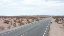 Man walking away in desert highway. A man walking on a road in the desert. 