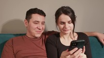 A Pair Seated on the Couch, Engrossed in Watching Content on Mobile Device - Close Up	