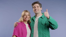 Stylish woman and man with hand sign like, thumbs up gesture. Happy couple, correct perfect choice, great deal, violet background. Positive friends smiles to camera, approval, trust concept. 4k