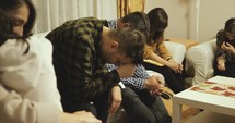 Several people praying in a living room