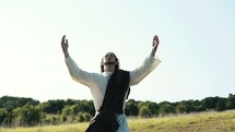 Jesus walking outdoors and raising his arms kneeling in prayer 