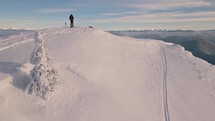 Man on ski standing on the top of snowy hill in Carpathian mountains with panoramic view
