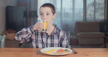 Young boy drinking orange juice for breakfast
