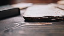 Slider shot of book with ancient writings, mystical secrets of past, mysteries of history lying on wooden table. Religious literature, archival manuscripts. Working atmosphere concept.