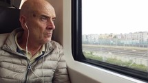 Elderly man is traveling by train and watching out