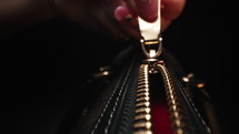 Golden zipper on handbag. Woman unzipping bag. Extreme macro. Metallic zip, detail. High quality 4k footage