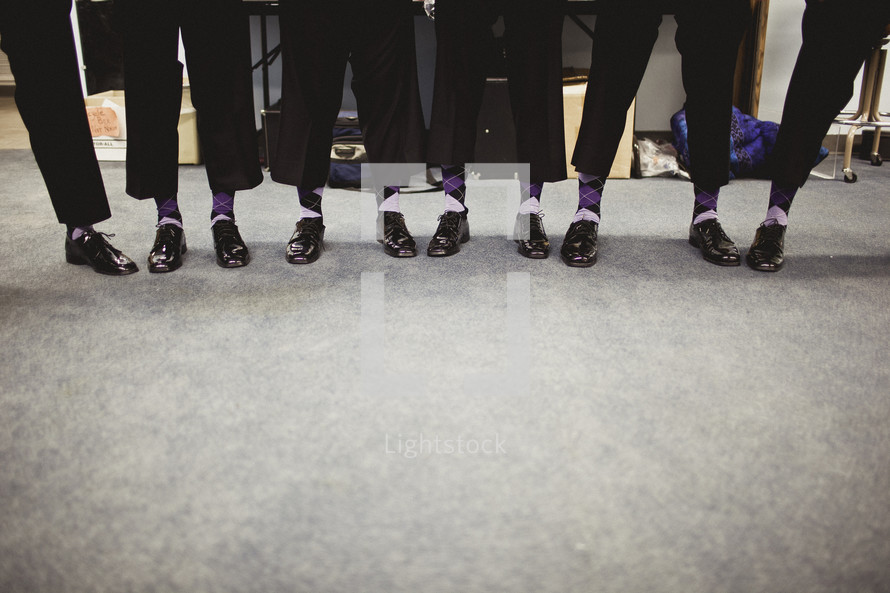 A group of men displaying their shoes and socks 