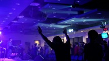 silhouettes with raised hands at a worship service 