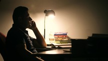 Man reading a Bible alone in a dark room 