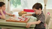 Young kids playing checkers together at home