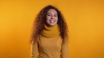 Young curly woman in total yellow look. Portrait of flirting beautiful girl on studio background