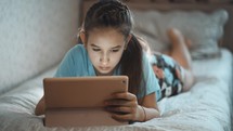 Kid child girl holding digital tablet. Teenager learning at home. Child Writing Homework for School, Girl Studying at Home, Homeschooling, Online Education. Modern Devices.