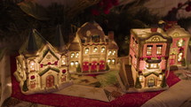 Decorative Christmas village with a pine garland behind it.