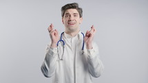 Mature 30s aged physician man in white medical coat form praying with hands on white background. Begs someone satisfy desires, help with, prays for luck. High quality 4k footage