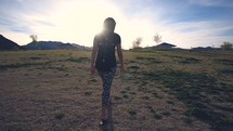 a woman walking across a prairie 