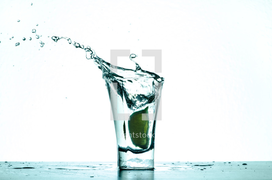 Splashing water in a shot glass with a lime.