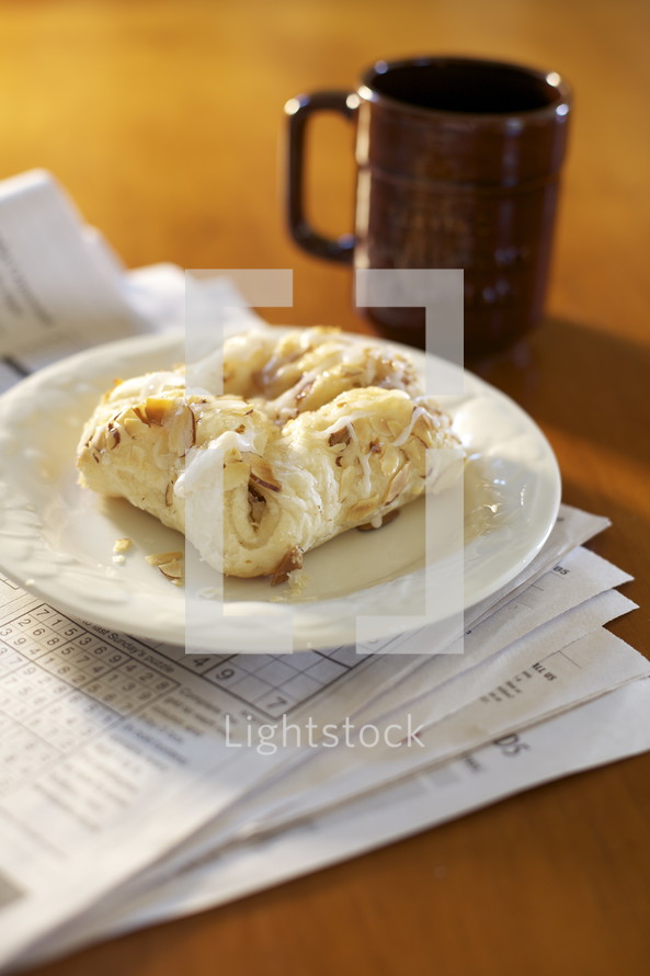 coffee and pastry on a plate on a newspaper 