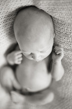 naked newborn baby lying on a blanket