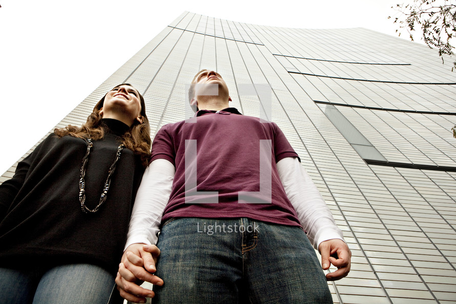 Couple holding hands in front of skyscraper building