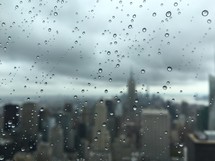 rain on a window and view of city skyscrapers 