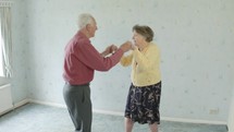 Senior couple dancing in their home