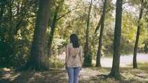 a woman standing still outdoors in a forest 