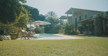 Tracking shot of a backyard of a large villa with a lawn and a swimming pool.