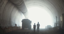 Workers walking inside a large tunnel construction project