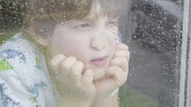boy looking out a window on a rainy day 