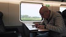 Elderly man is traveling by train and using the smartphone