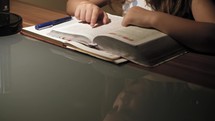 young girl sitting at a desk reading a Bible 