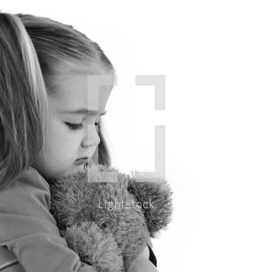 sad little girl holding a teddy bear 